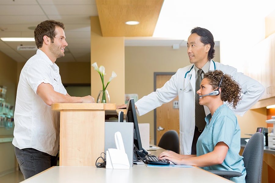 two medical staff speaking to man over a counter