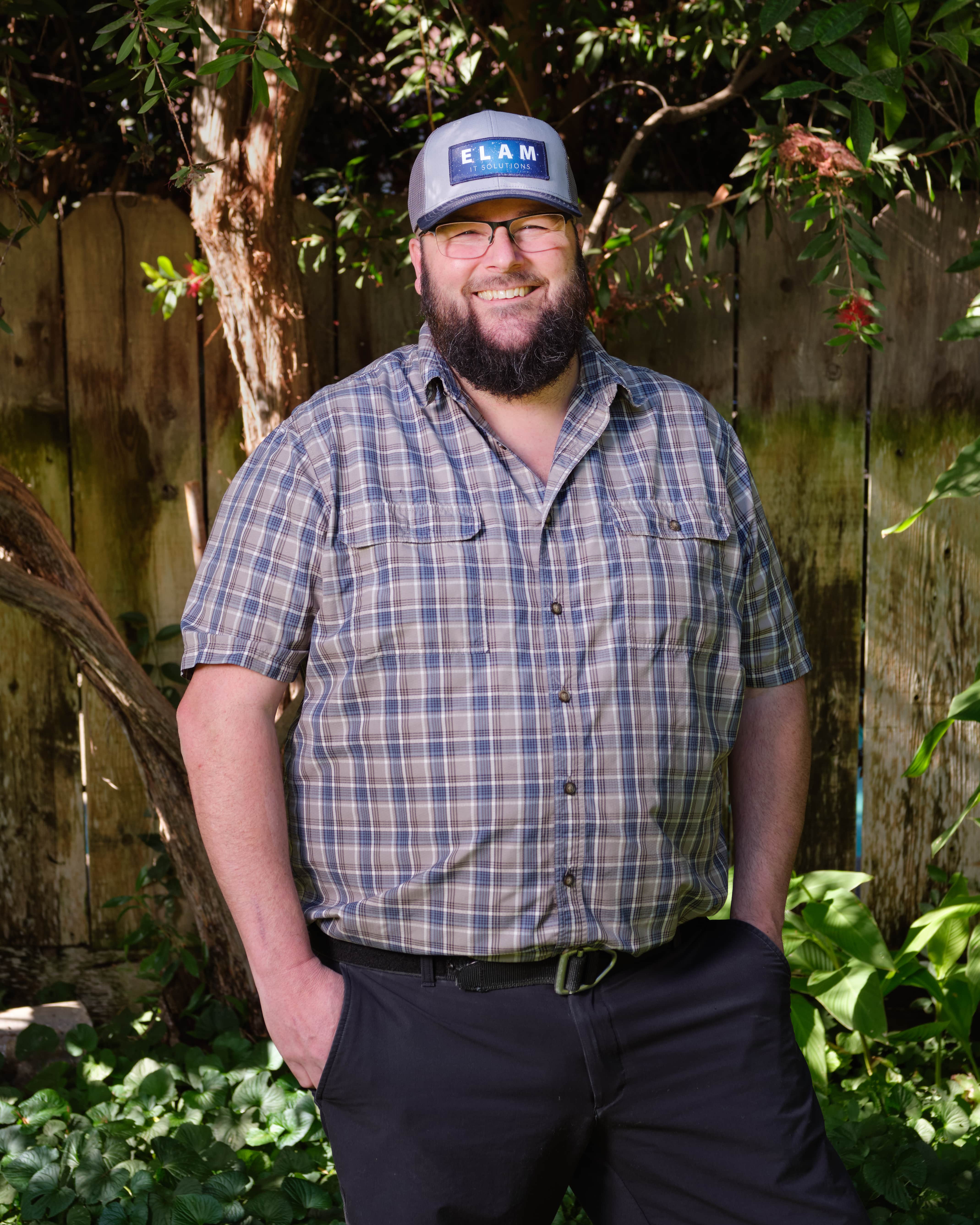 JD Elam, owner wearing plaid shirt with ELAM IT logo baseball cap