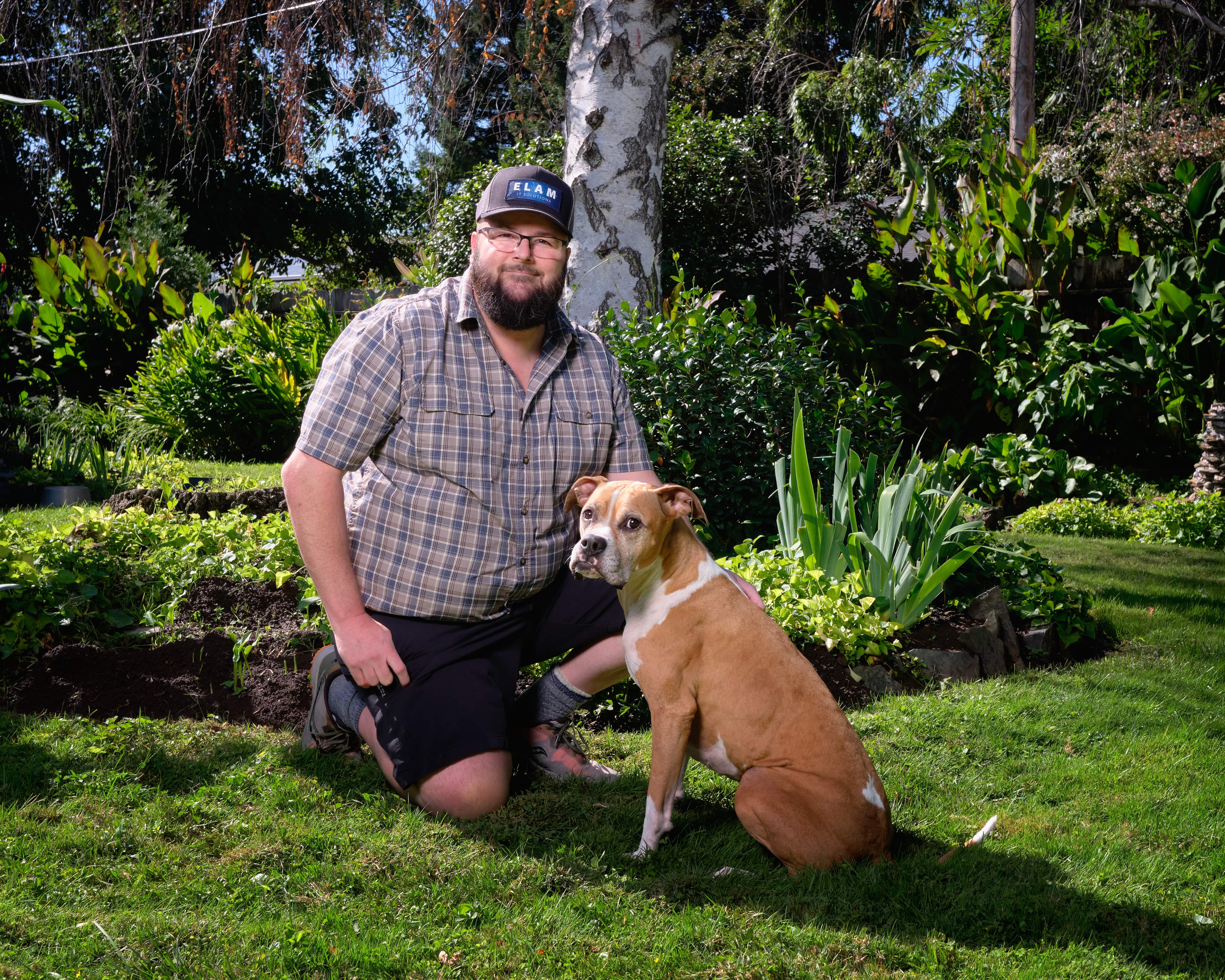 JD Elam, owner wearing plaid shirt with ELAM IT logo baseball cap with his dog