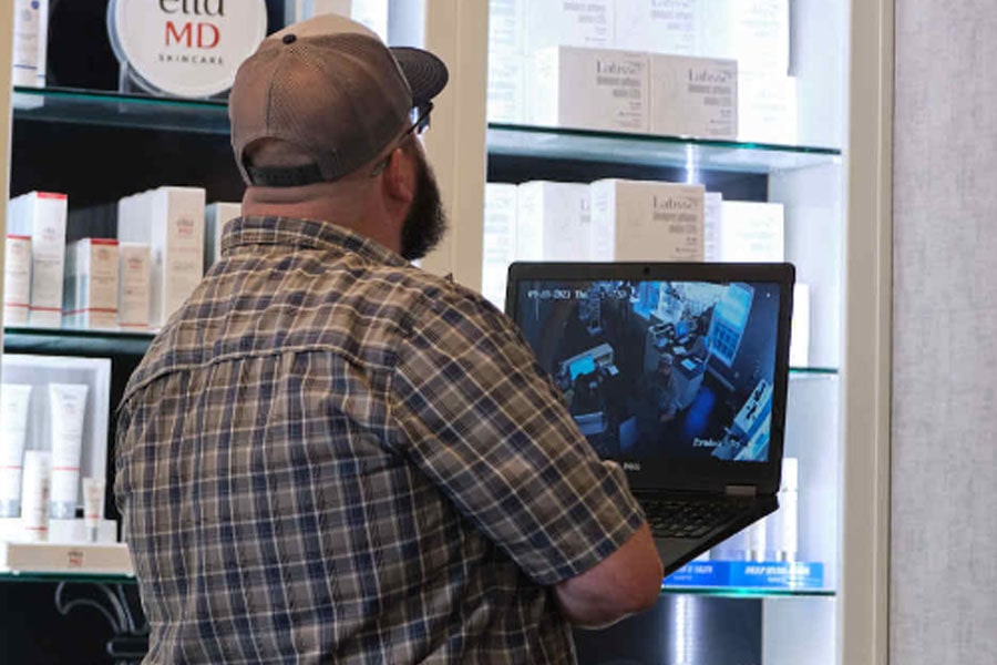 JD Elam, owner holding computer that is displaying security footage